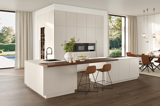 Modern kitchen with cooking island, bar top in wood look and fronts in Sand Perfect matt lacquer - clear, homely, open.